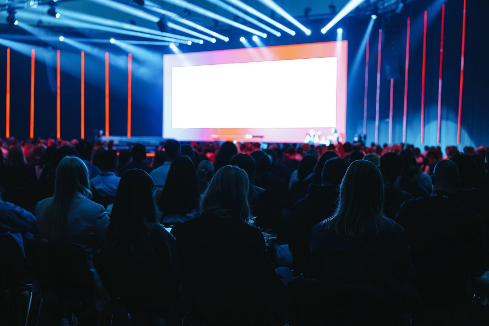A large formal conference with a lit stage and a blurred seated audience