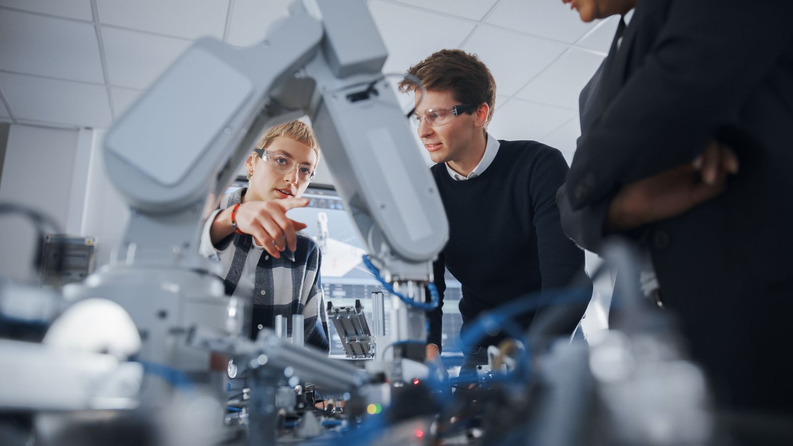 Students examining a robotic arm in a technology lab
