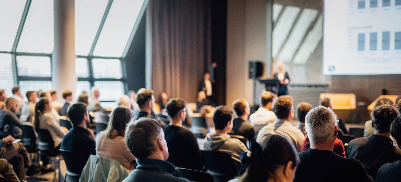Delegates seated at a conference seminar facing the stage